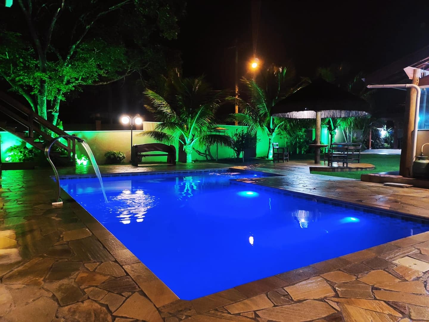 Piscina iluminada em LED à noite, vista do jardim