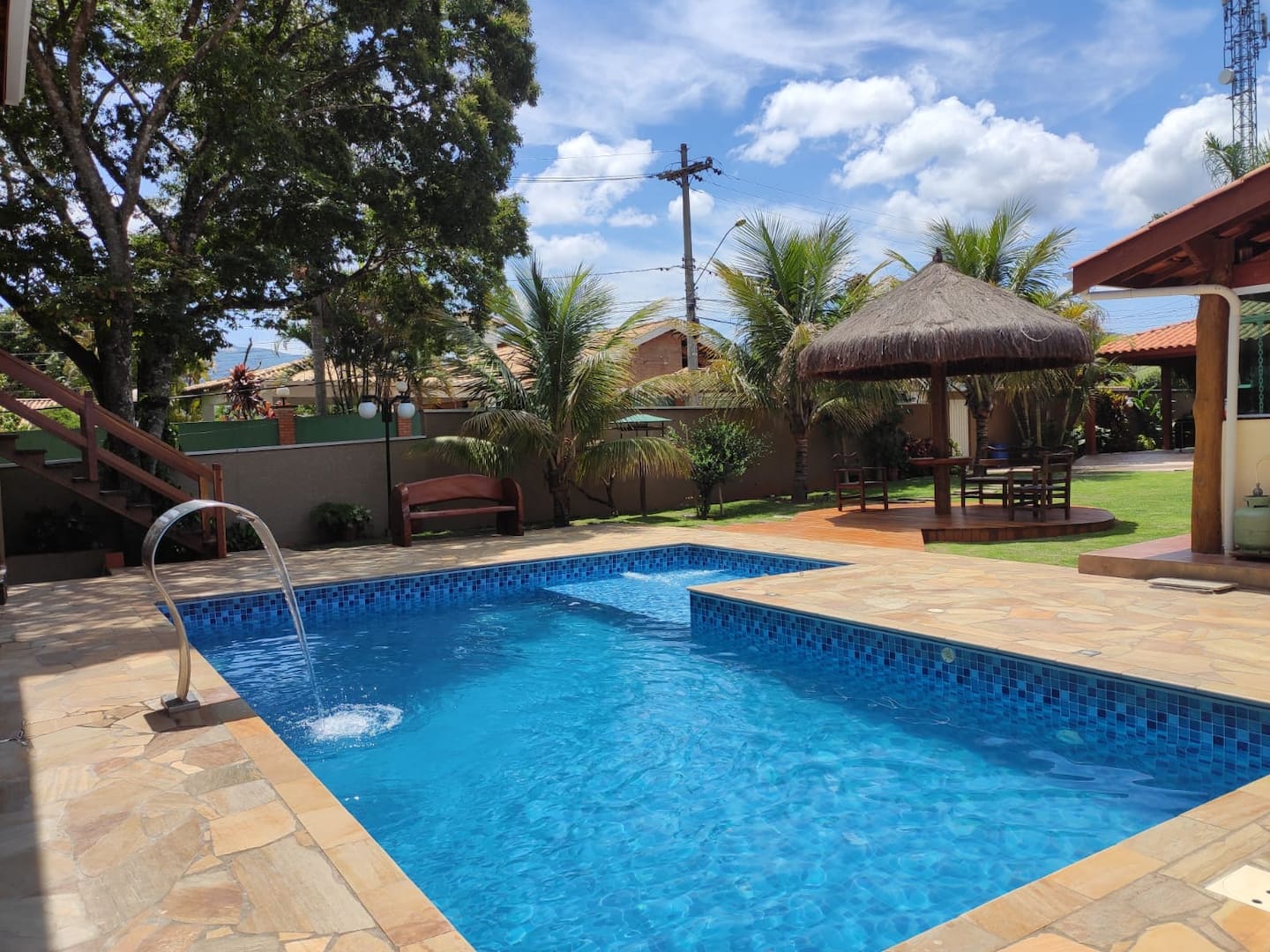 Piscina aquecida com deck, quiosque de palha e palmeiras