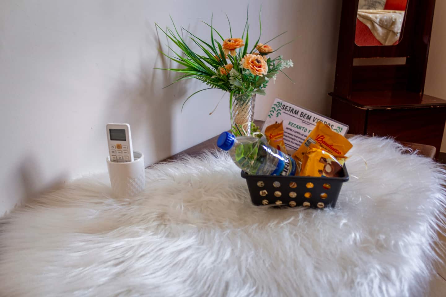 Cesta de boas-vindas sobre a cama, com flores e cortesias